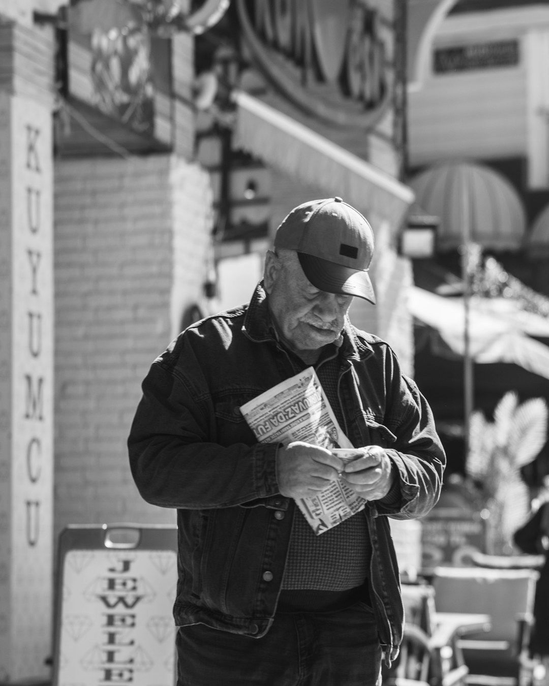 elderly-man-reading-a-newspaper-on-a-street-meienyduuy0