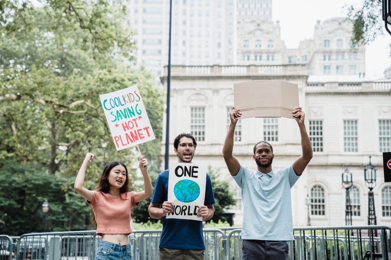 Young activists holding climate change signs in a city protest rally outdoors.